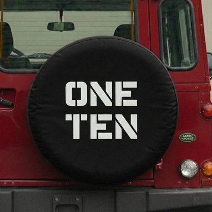 Red vehicle with a black spare tire cover displaying 'ONE TEN' on a blurred background